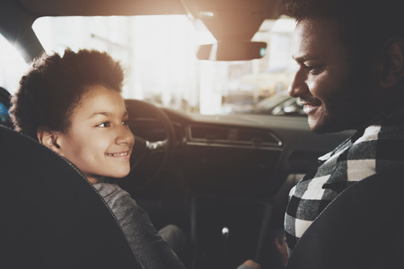 African american family at car dealership. Father and son are test driving new blue car.