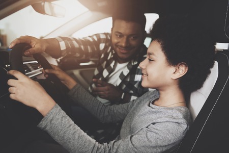 African american family at car dealership. Father and son are trying out new blue car.の写真素材