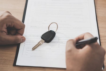 Close up father is signing papers for new grey car. African american family at car dealership.の写真素材