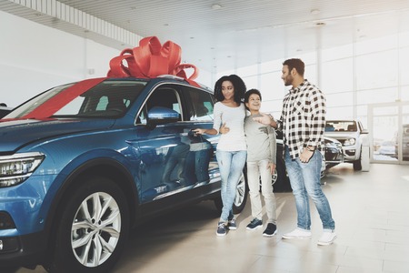 African american family at car dealership. Father, mother and son near new blue car.の写真素材