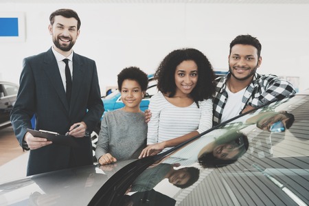 African american family at car dealership. Salesman is giving papers for new grey car.の写真素材