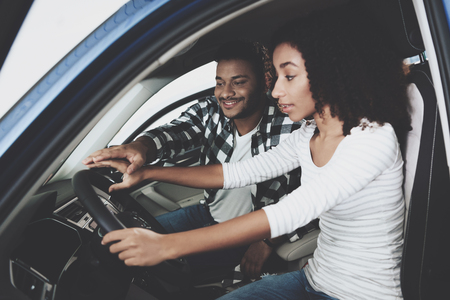 African american family at car dealership. Mother and father are trying out new blue car.の写真素材