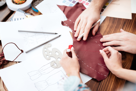 Top view two male and female fashion designers making cutout.