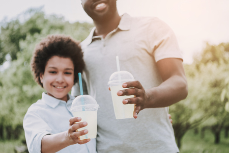 Father with son in park keep refreshing drinks in hands. Family relations concept.の写真素材