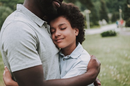 Father hugs his son in the park. They are happy.の写真素材