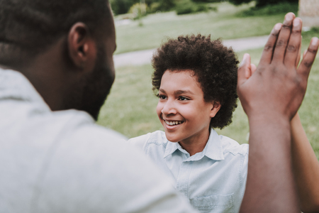 Father and son are happy in the park. They give five to each other.の写真素材