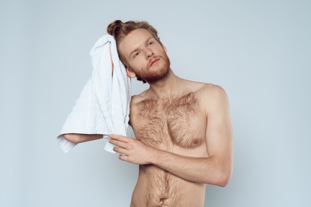 Red haired bearded man is wiping wet hair by towel. Personal hygiene. Morning hygiene procedures.の写真素材
