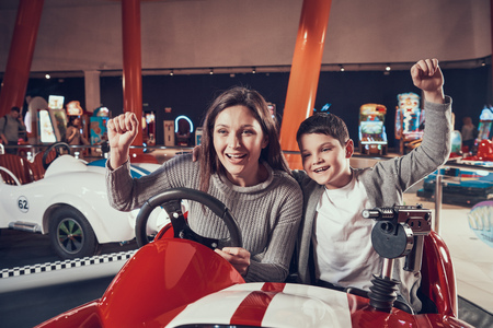 Happy smiling mother and son sitting on toy car. Spending holiday together with family....
