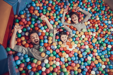 Top view. Happy family lying in pool with balls. Family rest, leisure concept. Spending holiday together. Entertainment center, mall, amusement park.の写真素材
