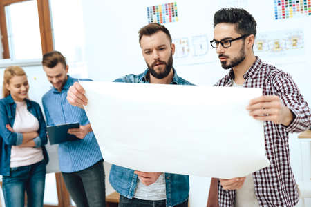 Team of designers architects looking at blueprint.