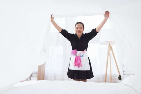Asian housekeeper makes a bed and rejoices.