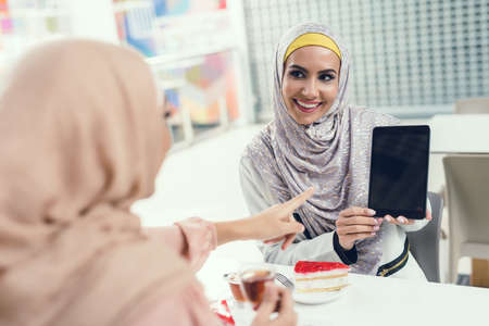 Arabian Women Sitting in Cafe in Mall with Tablet.の写真素材