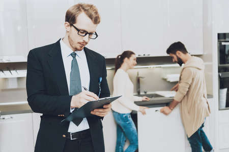 A man with glasses stands in suit and takes notes.の写真素材