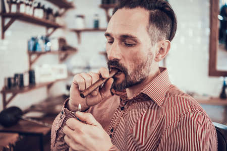 A man sits in a barbershop and smokes a cigarette.の写真素材