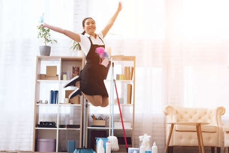 Young Asian maid jumps while cleaning in room.の写真素材