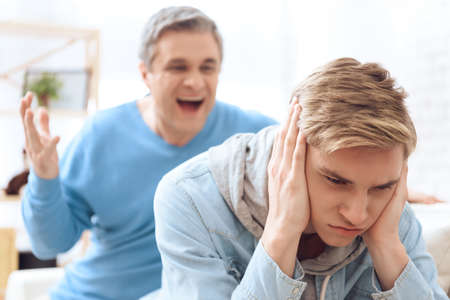 Son closed his ears while dad yells at him at homeの写真素材