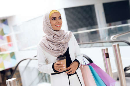 Arabian Woman with Cup of Coffee Standing in Mall.の写真素材