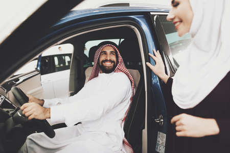 Arab sitting in new car and looking at arab woman.の写真素材