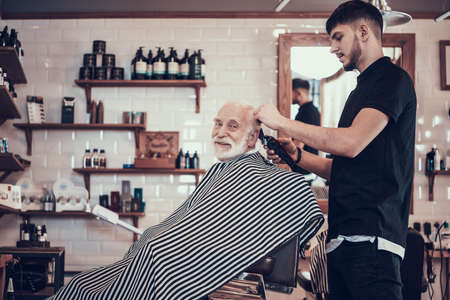 A hairdresser stands in a barbershop and cuts.の写真素材
