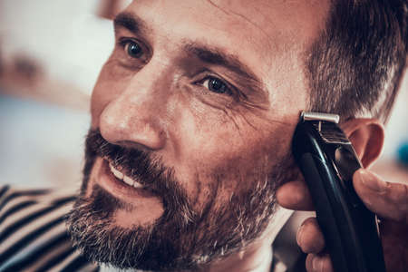 Man sits in barbershop while he gets new haircut.の写真素材