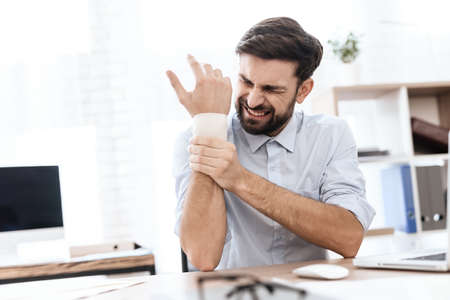 Man sits at work and holding on to a sore arm.の写真素材