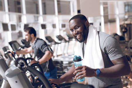 Two men are engaged on treadmills in modern gym.の写真素材