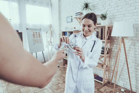 Doctor in a white coat takes a bribe and smiles.