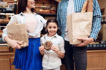 Young Happy Family Buying Bread in Modern Bakery.の写真素材