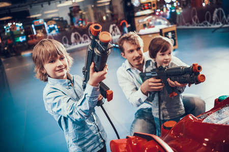 Dad teaches his sons to play shooting games.