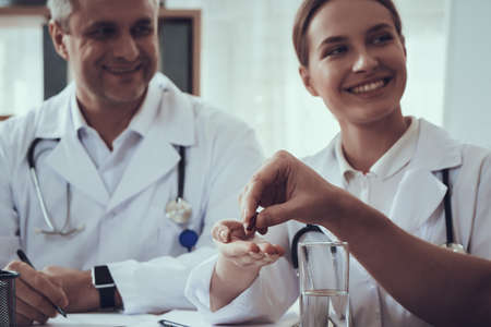 Woman doctor gives a sick patient pill and water.の写真素材