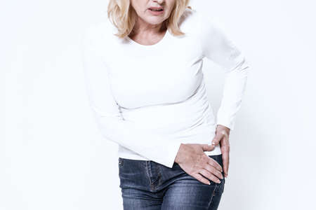 Adult woman holds on to hip and feels severe pain.の写真素材