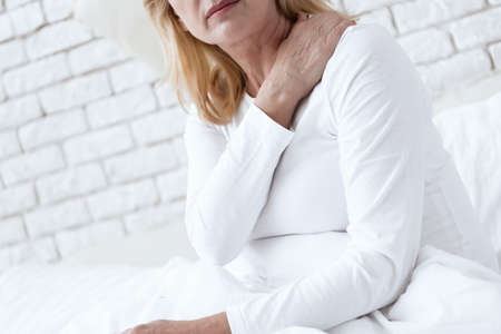 A woman holding on to her shoulder that hurts.の写真素材