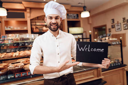Young Man with Welcome Sign Standing in Bakery.の写真素材