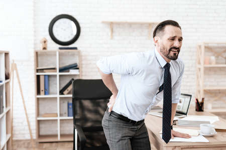 Man in office grabbed his sore back and suffers.