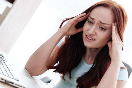Girl at workplace and suffers from severe pain.の写真素材