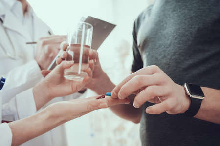 Man takes a pill and water from the doctor.の写真素材