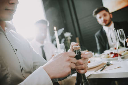 Man opens champagne at his birthday party.