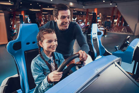 Dad helps his daughter drive a computer game.