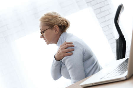 A woman holding on to her shoulder that hurts.