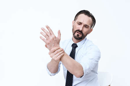 A man stands on white and holds his wrist.の写真素材