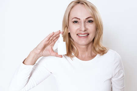 Blonde woman stands with nasal spray in her hands.の写真素材