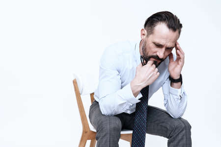 A man in a shirt sits and feels pain in his head.の写真素材