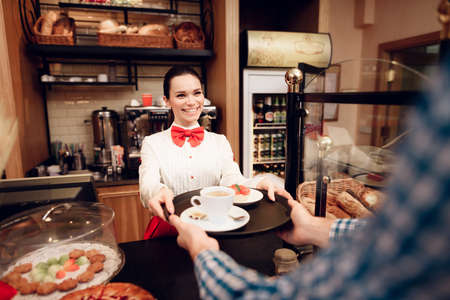 Smiling Girl Giving Cakes and Cup of Coffee to Manの写真素材