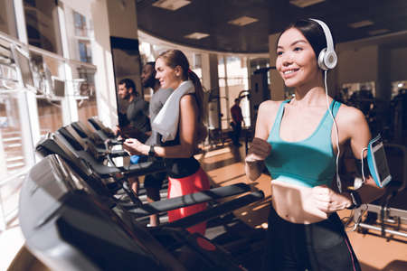 Girl in headphones is training in the gym.