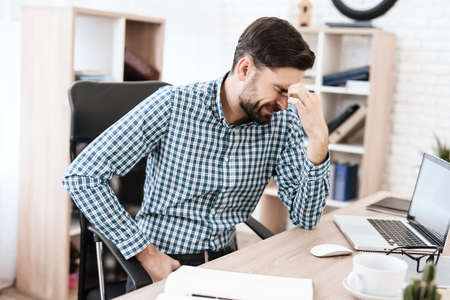 Man suffers severe pain while sitting at his desk.の写真素材