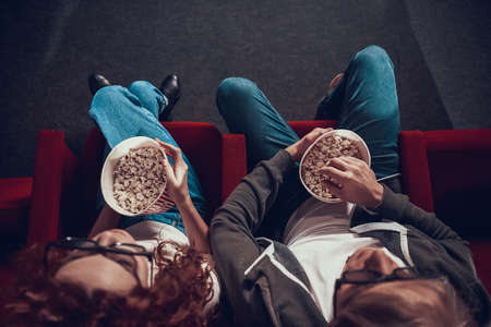 Blond guy with red haired girl eating popcorn.