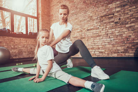 Mom helps her daughter sit on the twine in gym.の写真素材