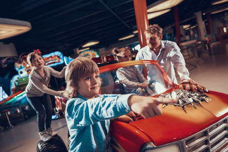 Dad stands near his daughter who drives a toy car.の写真素材