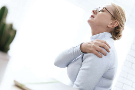 A woman holding on to her shoulder that hurts.の写真素材