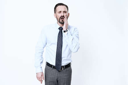 A man in a tie stands and holds on to a bad tooth.の写真素材